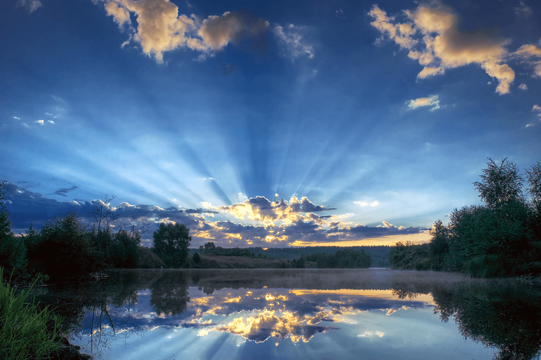 Sunset over a large mass of water and deep blue colored clouds